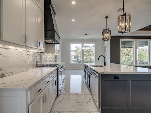 kitchen featuring stainless steel appliances, sink, hanging light fixtures, and a large island with sink