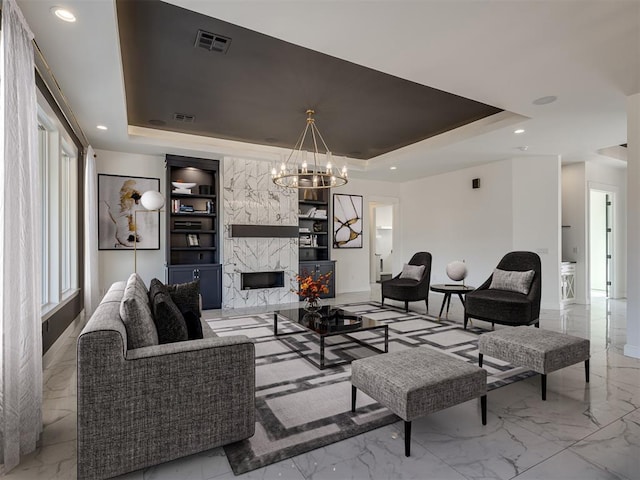 living room featuring an inviting chandelier, a high end fireplace, a tray ceiling, and built in features