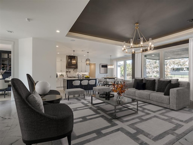 living room with a chandelier, a raised ceiling, and sink