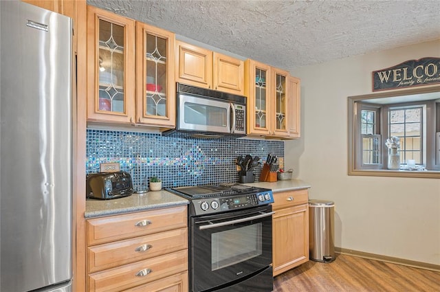 kitchen featuring light brown cabinets, tasteful backsplash, stainless steel appliances, and light hardwood / wood-style flooring