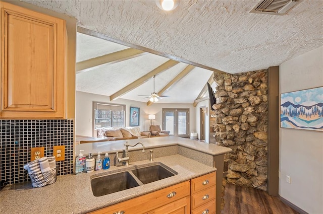 kitchen featuring decorative backsplash, ceiling fan, dark wood-type flooring, sink, and lofted ceiling with beams