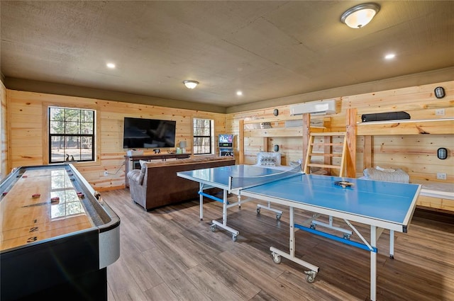 game room with hardwood / wood-style flooring, wooden walls, and a wall mounted AC