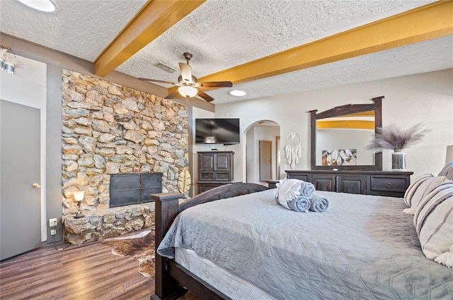 bedroom with hardwood / wood-style floors, ceiling fan, beam ceiling, and a textured ceiling