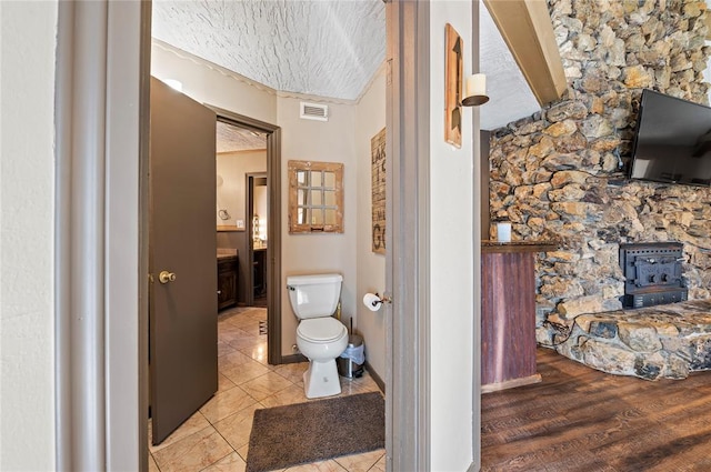 bathroom with a wood stove, hardwood / wood-style floors, and toilet