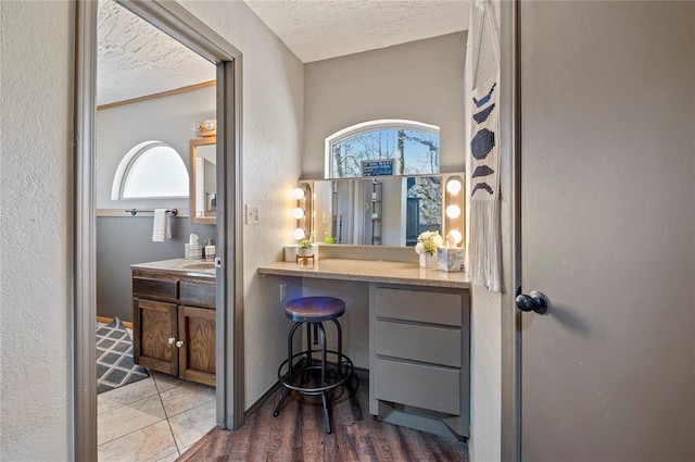 bathroom with hardwood / wood-style floors, vanity, a healthy amount of sunlight, and a textured ceiling