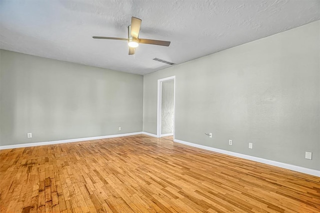 empty room with light wood-style floors, visible vents, ceiling fan, and baseboards