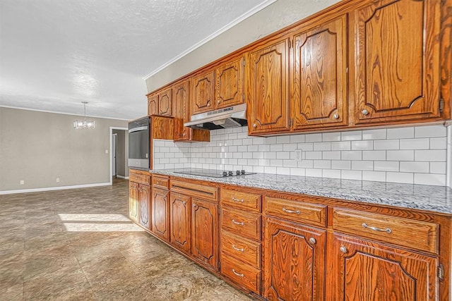 kitchen featuring black electric stovetop, under cabinet range hood, baseboards, brown cabinets, and tasteful backsplash