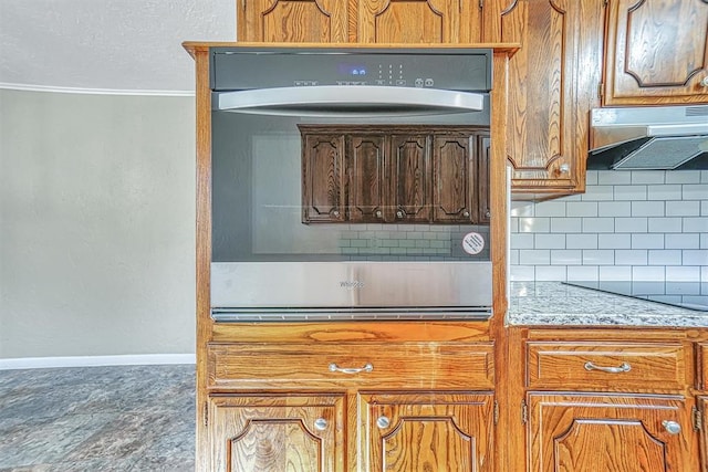 kitchen with backsplash, oven, under cabinet range hood, baseboards, and black electric cooktop