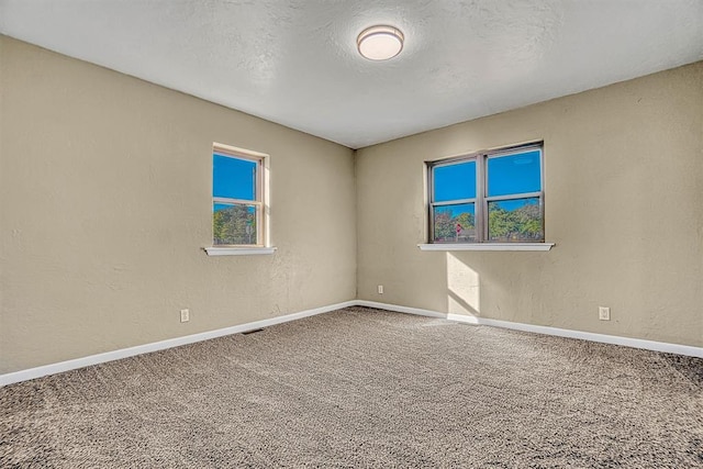 carpeted empty room with visible vents, baseboards, a textured ceiling, and a textured wall