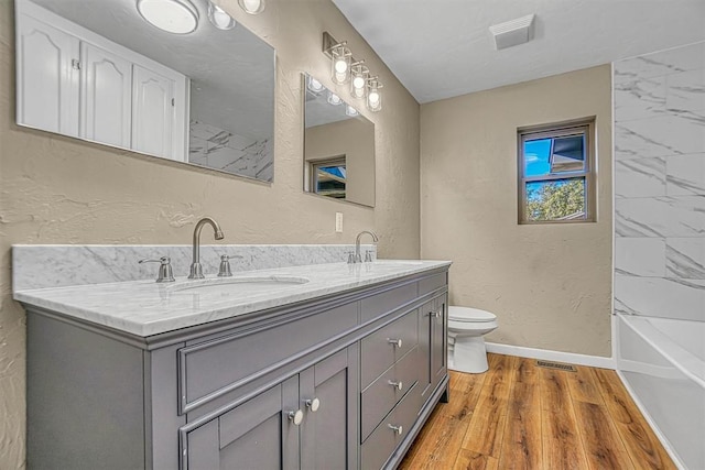 bathroom featuring baseboards, a sink, toilet, and wood finished floors