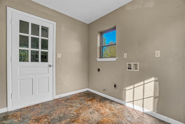 laundry area featuring stone finish floor, laundry area, a textured wall, and electric dryer hookup