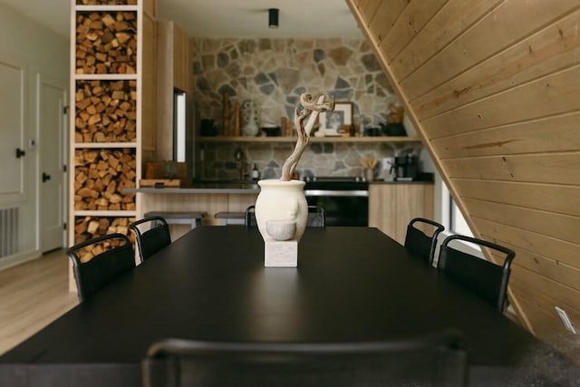 dining space featuring wooden walls, wooden ceiling, and hardwood / wood-style flooring