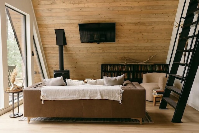 sitting room featuring a wood stove, wooden walls, and light hardwood / wood-style floors