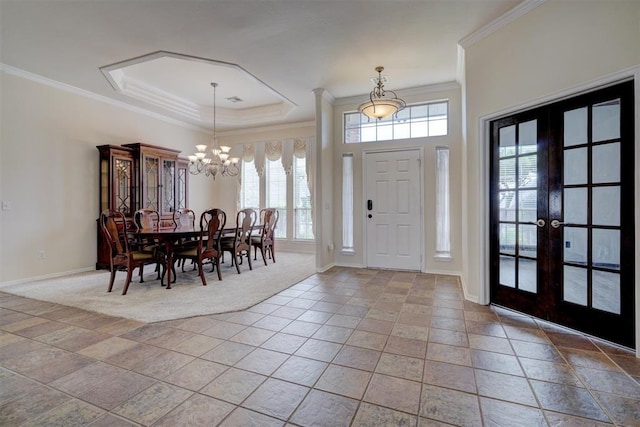 entryway with an inviting chandelier, ornamental molding, a tray ceiling, and french doors