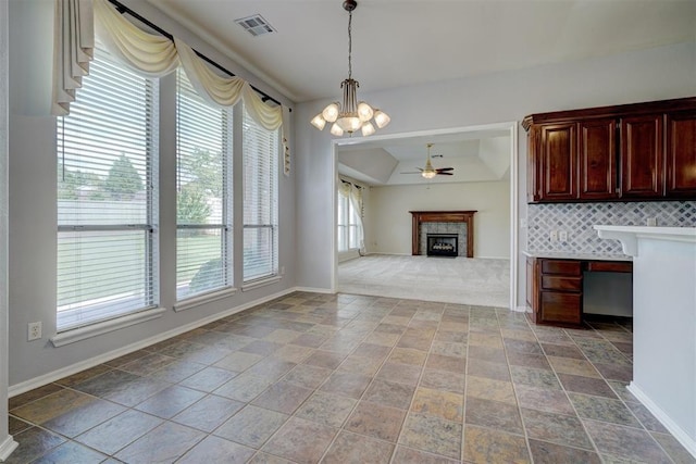 interior space with a tile fireplace, ceiling fan with notable chandelier, and a healthy amount of sunlight