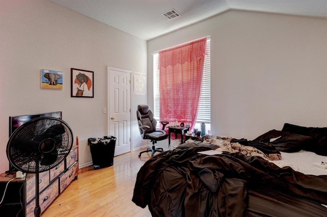 bedroom with lofted ceiling, light wood-style floors, and visible vents