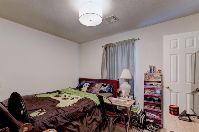 bedroom with a textured ceiling, wood finished floors, and visible vents