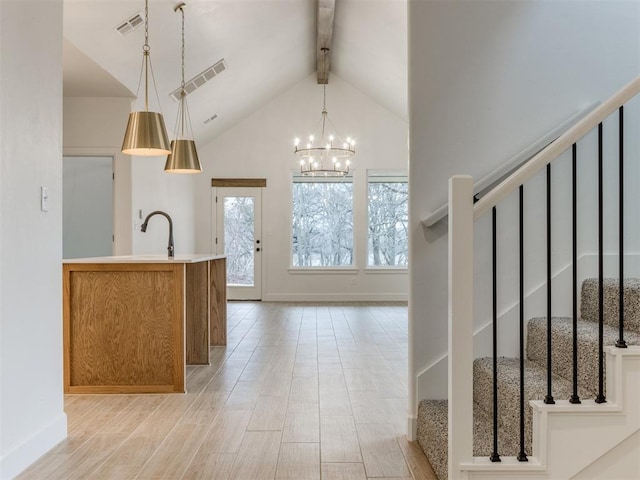 kitchen with high vaulted ceiling, beamed ceiling, light wood-type flooring, hanging light fixtures, and an inviting chandelier