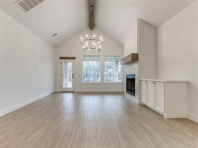 unfurnished living room with an inviting chandelier, beam ceiling, high vaulted ceiling, light hardwood / wood-style floors, and a large fireplace