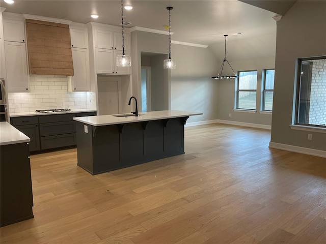 kitchen featuring a center island with sink, light hardwood / wood-style floors, white cabinetry, and sink