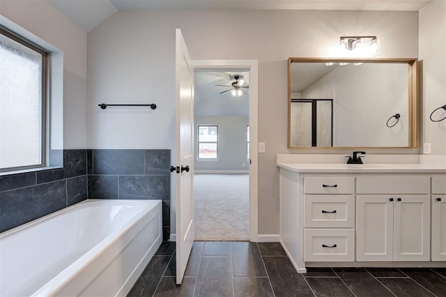 bathroom featuring baseboards, ceiling fan, vaulted ceiling, a bath, and vanity