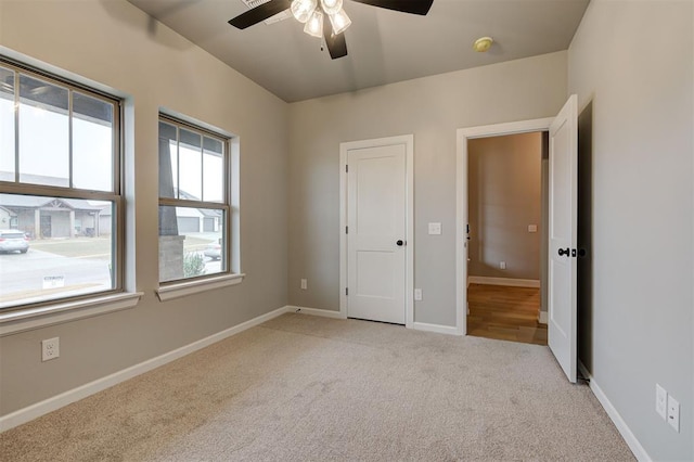 unfurnished bedroom featuring baseboards, light colored carpet, and a ceiling fan