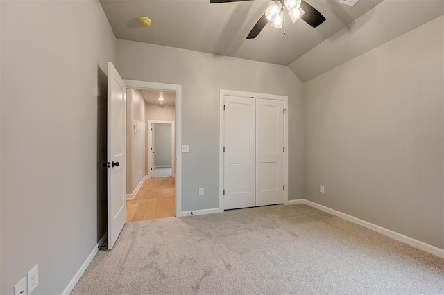 unfurnished bedroom featuring baseboards, lofted ceiling, carpet flooring, a closet, and a ceiling fan