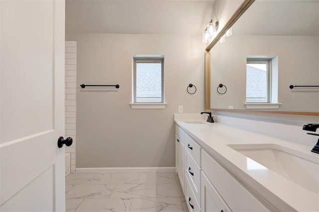 bathroom with a sink, baseboards, marble finish floor, and double vanity