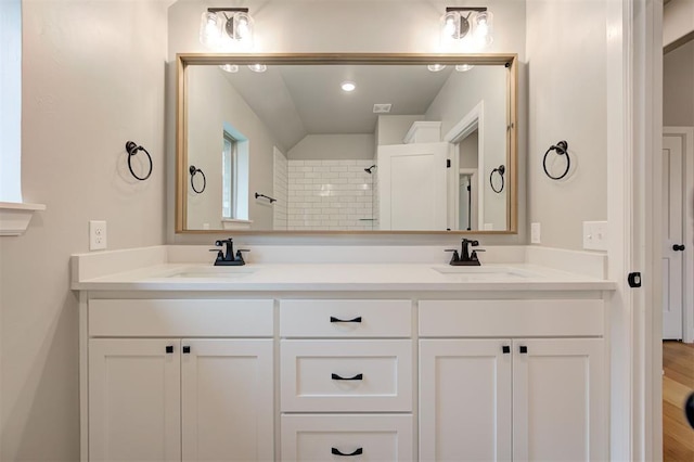 full bathroom with double vanity, a shower, and a sink