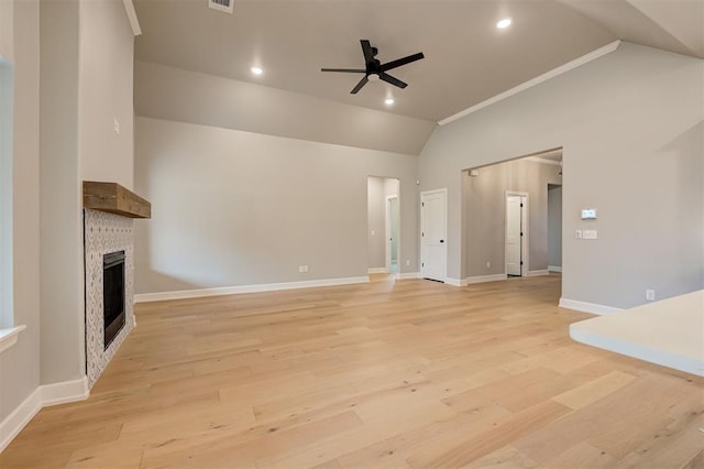 unfurnished living room with light wood-type flooring, lofted ceiling, a fireplace, and a ceiling fan