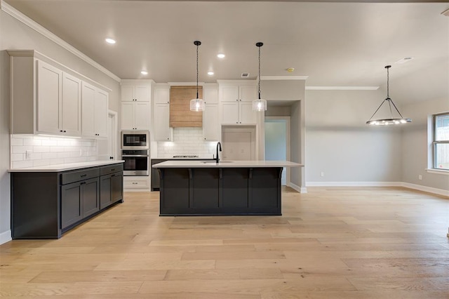 kitchen featuring a sink, decorative backsplash, light countertops, appliances with stainless steel finishes, and white cabinetry