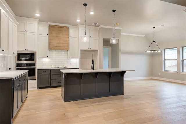 kitchen featuring tasteful backsplash, light wood finished floors, light countertops, stainless steel appliances, and a sink