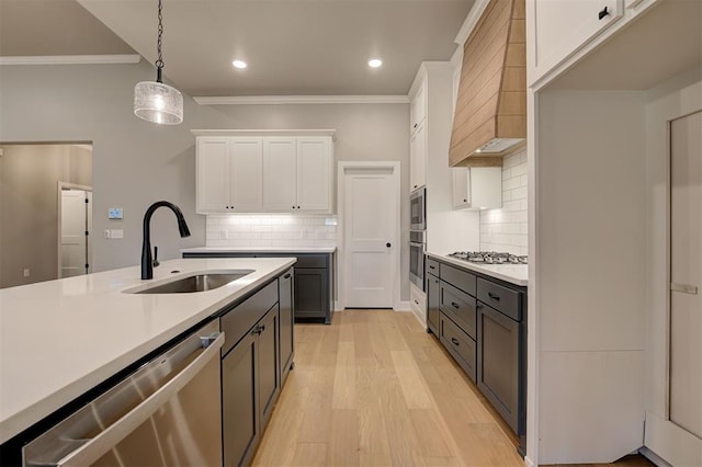 kitchen with custom exhaust hood, stainless steel appliances, light countertops, and a sink