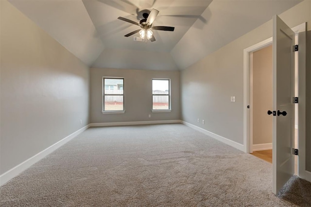 carpeted spare room featuring vaulted ceiling, a ceiling fan, and baseboards