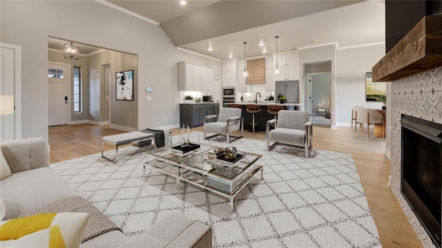 living room featuring baseboards, lofted ceiling, ornamental molding, a tile fireplace, and light wood-style floors