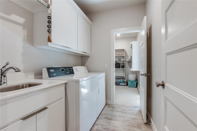 laundry room with light hardwood / wood-style floors, cabinets, sink, and washing machine and clothes dryer