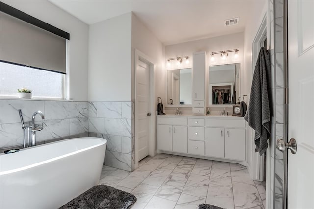 bathroom featuring a bathing tub, vanity, and tile walls