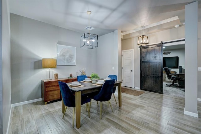 dining space with a barn door and light hardwood / wood-style floors