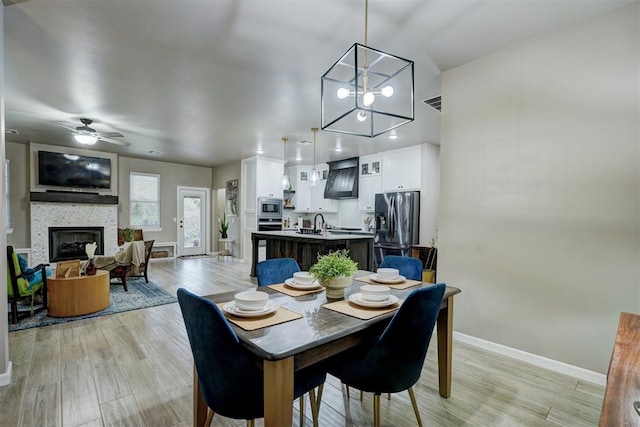 dining room featuring light wood-type flooring and ceiling fan with notable chandelier