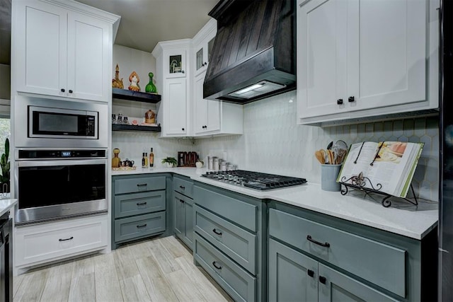 kitchen with gray cabinetry, custom exhaust hood, light wood-type flooring, white cabinetry, and stainless steel appliances