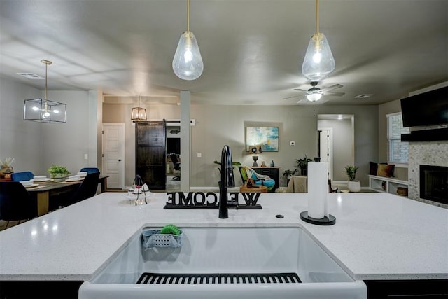 kitchen with sink, hanging light fixtures, and a kitchen island with sink