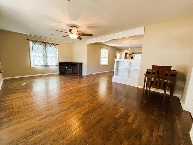 unfurnished living room featuring dark wood-type flooring and ceiling fan with notable chandelier