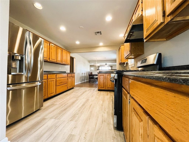 kitchen with kitchen peninsula, appliances with stainless steel finishes, light wood-type flooring, and dark stone counters