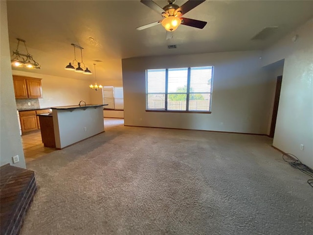 unfurnished living room with ceiling fan with notable chandelier and light colored carpet