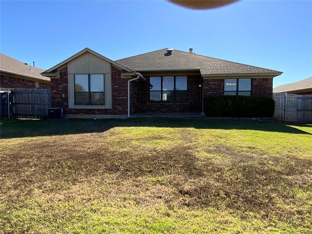 rear view of property featuring a lawn and central AC unit