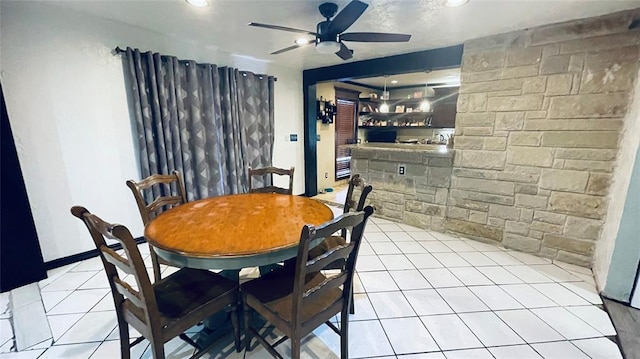 tiled dining space featuring ceiling fan and indoor bar