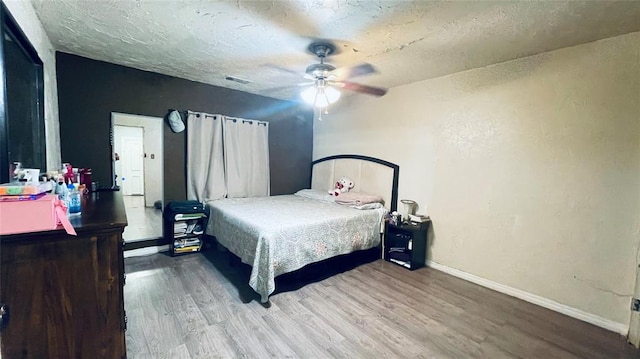 bedroom with ceiling fan, wood-type flooring, and a textured ceiling