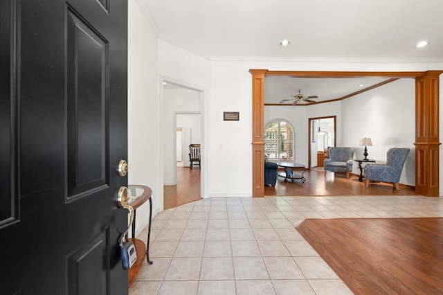 entryway with decorative columns, ornamental molding, ceiling fan, and light tile patterned flooring