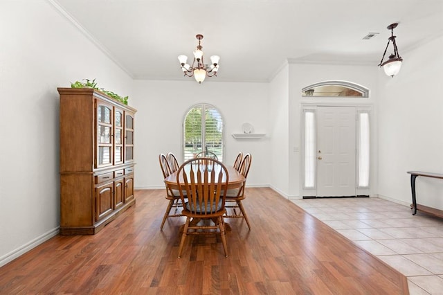 dining space featuring a chandelier, visible vents, ornamental molding, and light wood finished floors