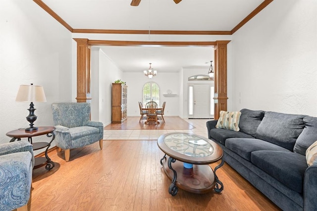 living room featuring ornamental molding, light wood-type flooring, decorative columns, and ceiling fan with notable chandelier